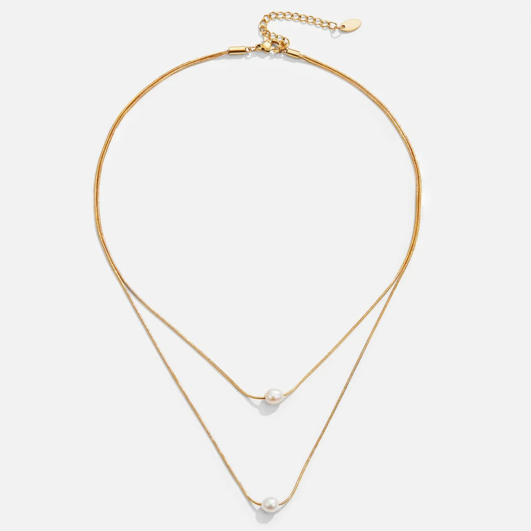 Sabina – Doble capa de cadena de oro con piedra oscura.