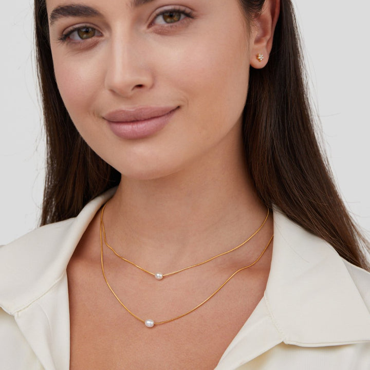 Sabina – Doble capa de cadena de oro con piedra oscura.