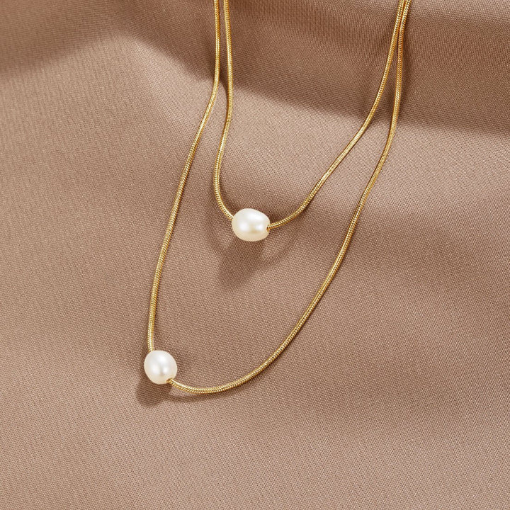 Sabina – Doble capa de cadena de oro con piedra oscura.