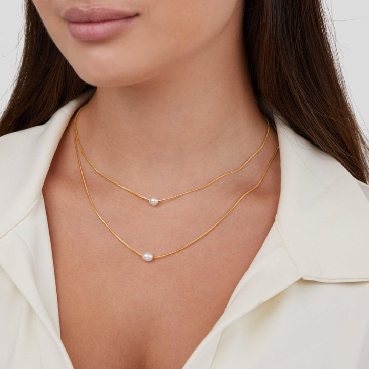 Sabina – Doble capa de cadena de oro con piedra oscura.