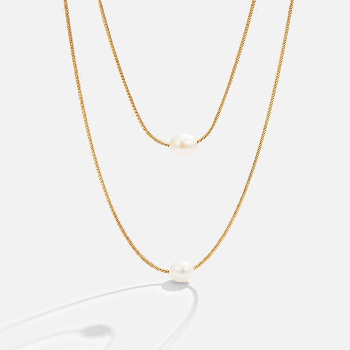 Sabina – Doble capa de cadena de oro con piedra oscura.
